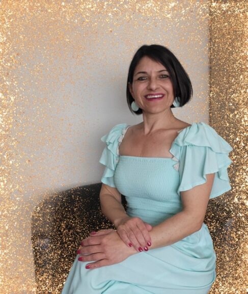 Heilerin und Mentorin Michèle Damonte in einem Sessel sitzend, mit gold glitzerndem Rahmen